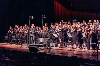 Het studentenorkest speelt staand voor het publiek. Voor hen staat een trotse dirigent.