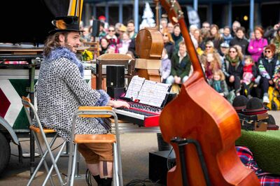 Muzikant speelt keyboard op een podium, met contrabas op de voorgrond en publiek dat rondom kijkt.