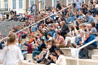 Publiek zit op de trappen en klapt tijdens een optreden van Nijmegen Klinkt! aan de Waal.