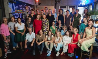 Groepsfoto van een grote groep collega’s die samen poseren in een kleurrijke, creatieve ruimte